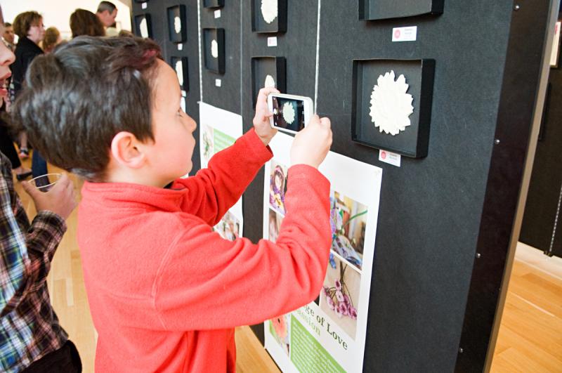 Griffin Ferrick, a second grader, takes a picture of his sister Delaney’s artwork at the "Bread and Roses" gallery. BY DOLLY GENANNT